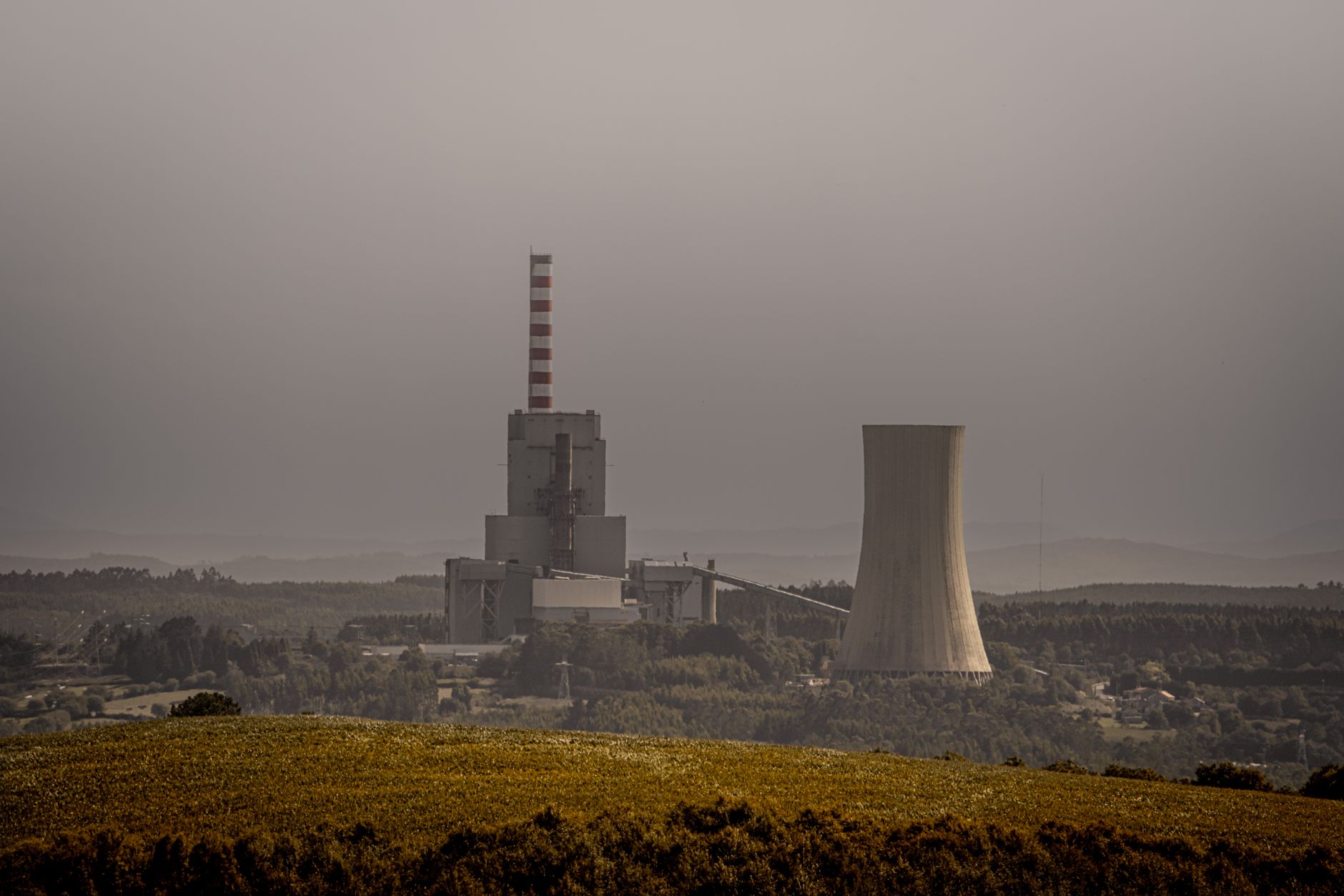 A coal-fired power plant emits smoke on an overcast day, highlighting energy and environmental issues.