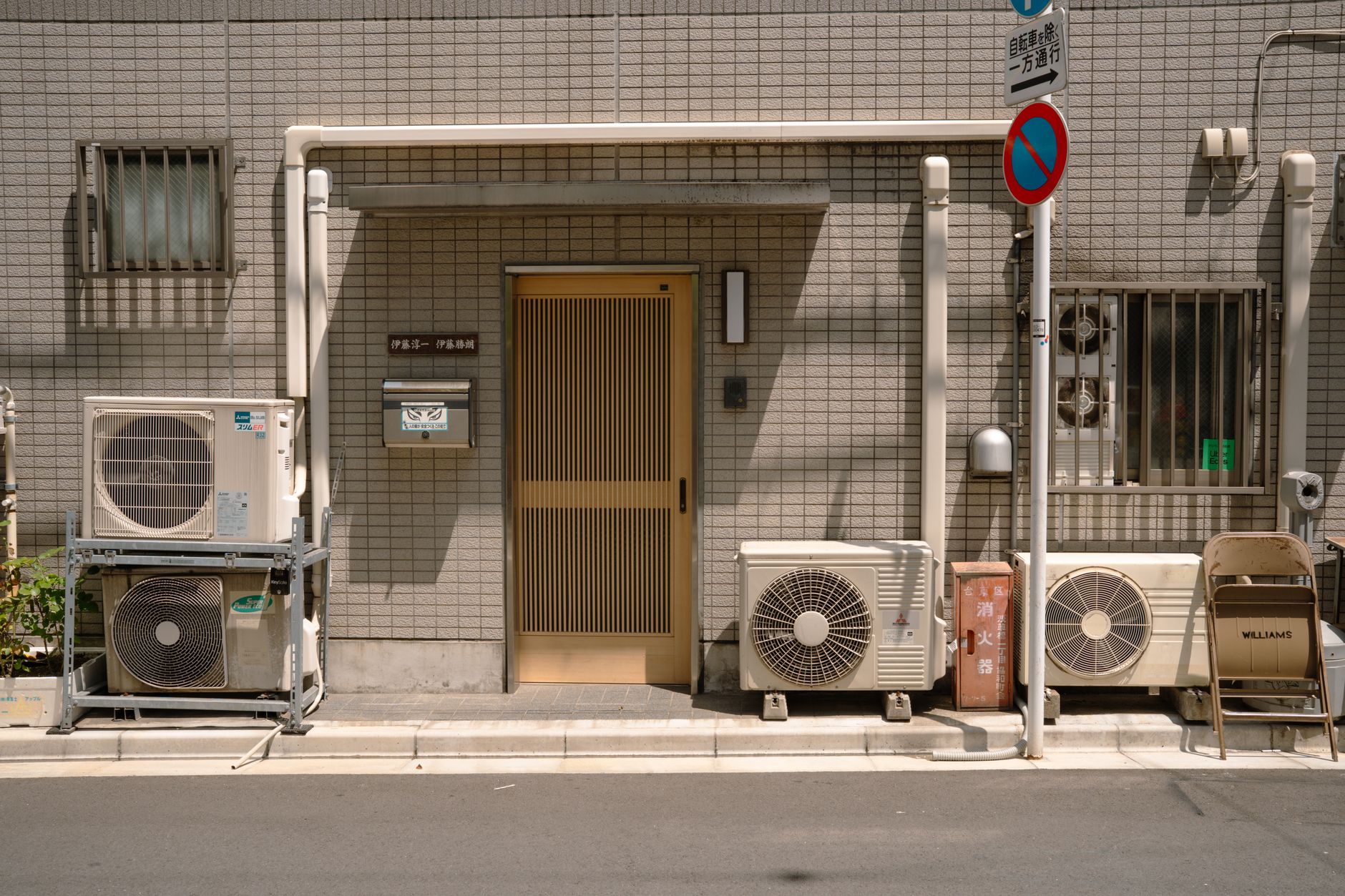 A minimalist facade with air conditioners and a no parking sign in Tokyo, Japan.