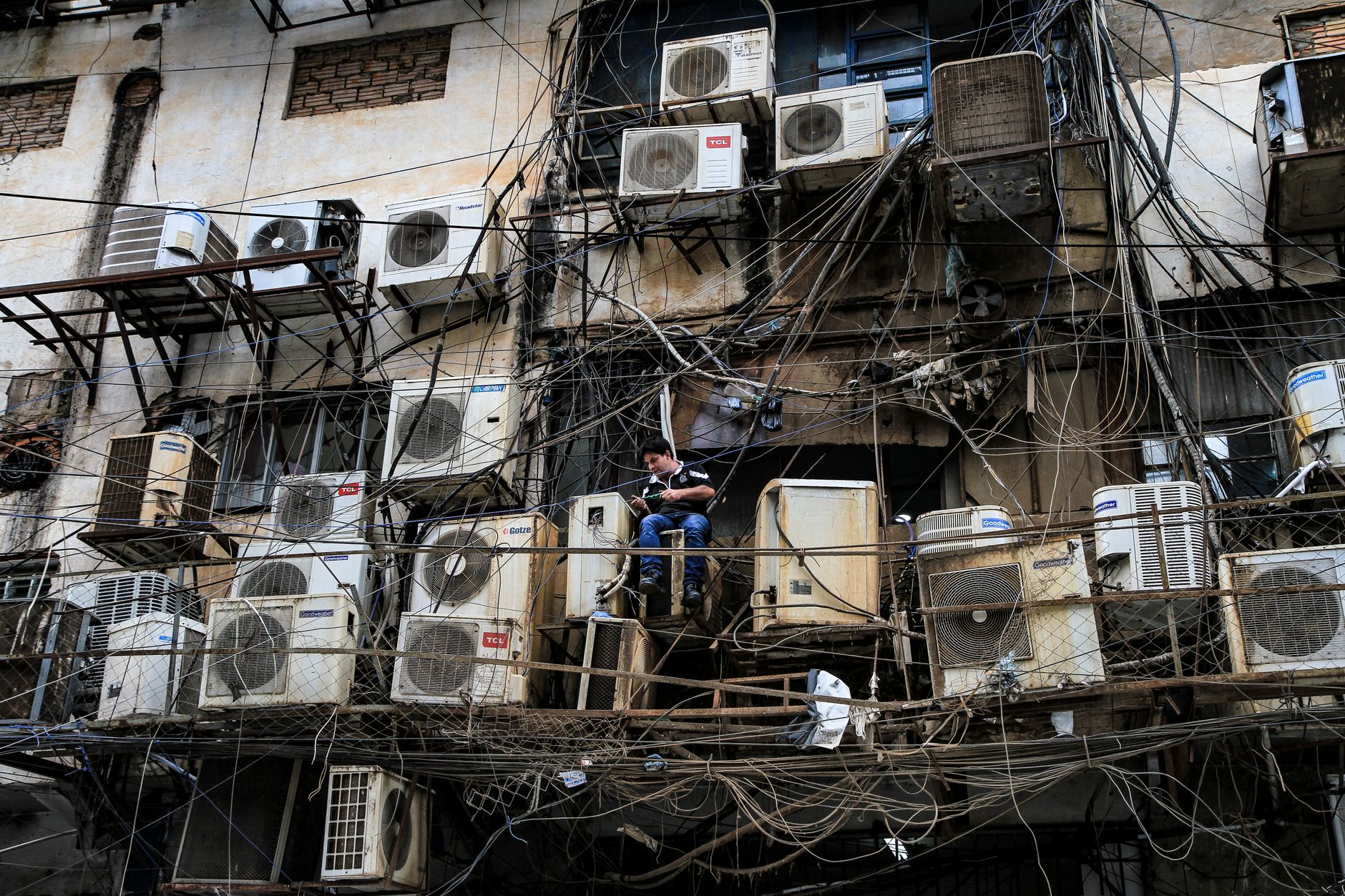Chaotic array of air conditioning units and wires on an urban building facade in Asunción, Paraguay.