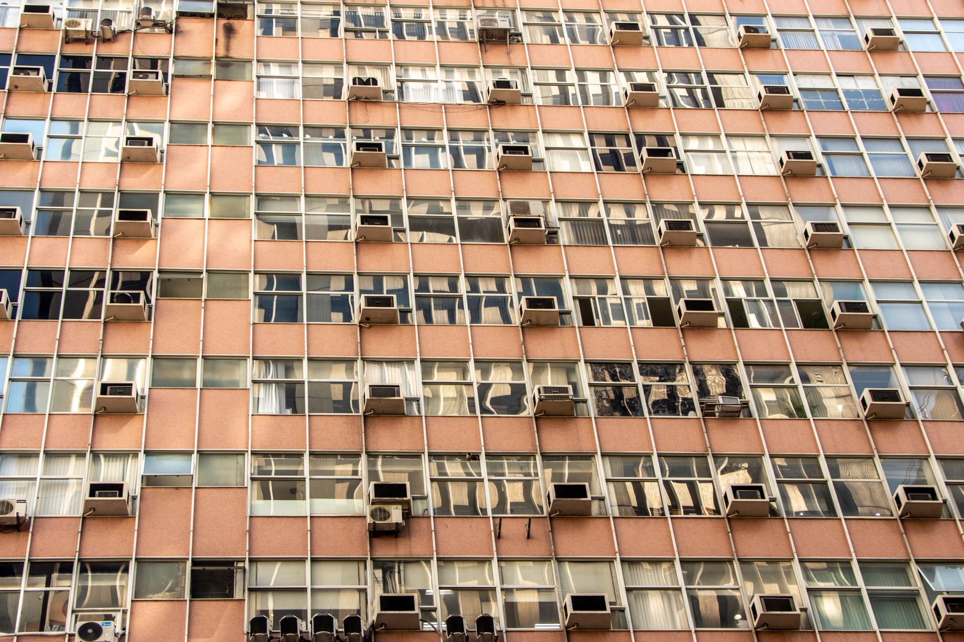 Close-up of an urban apartment building facade with multiple windows and air conditioning units.