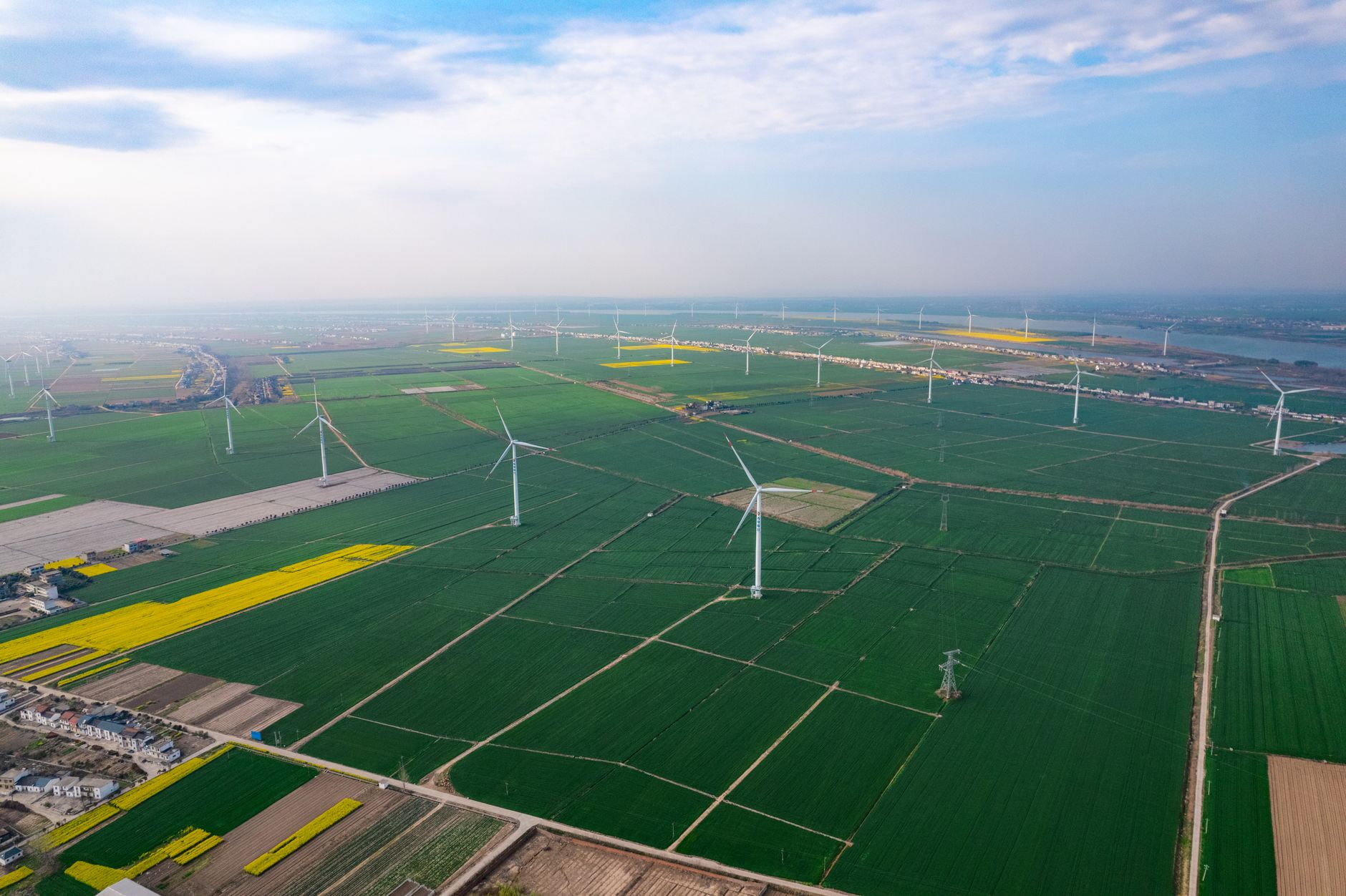 Expansive aerial view of wind turbines across farmland in Jiujiang, China, highlighting sustainable energy.