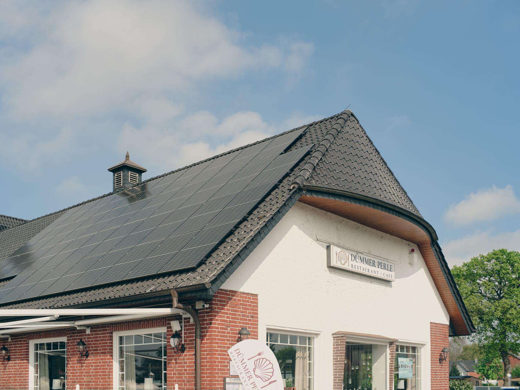 A red brick building with solar panels on the roof, under a clear blue sky, symbolizing sustainability and renewable energy.