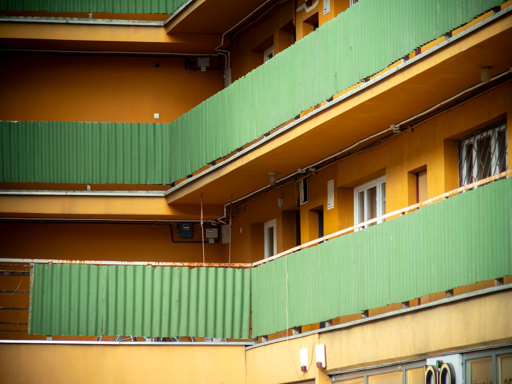 A vibrant view of apartment balconies with green panels and yellow walls in Poland.