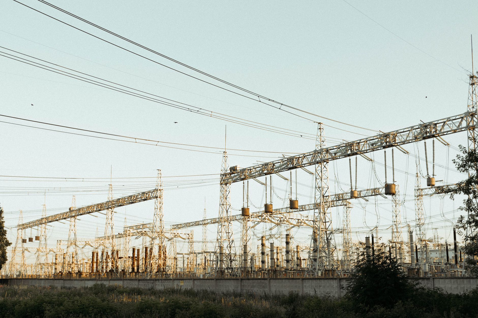 A wide view of an industrial electrical substation with power lines and towers outdoors.