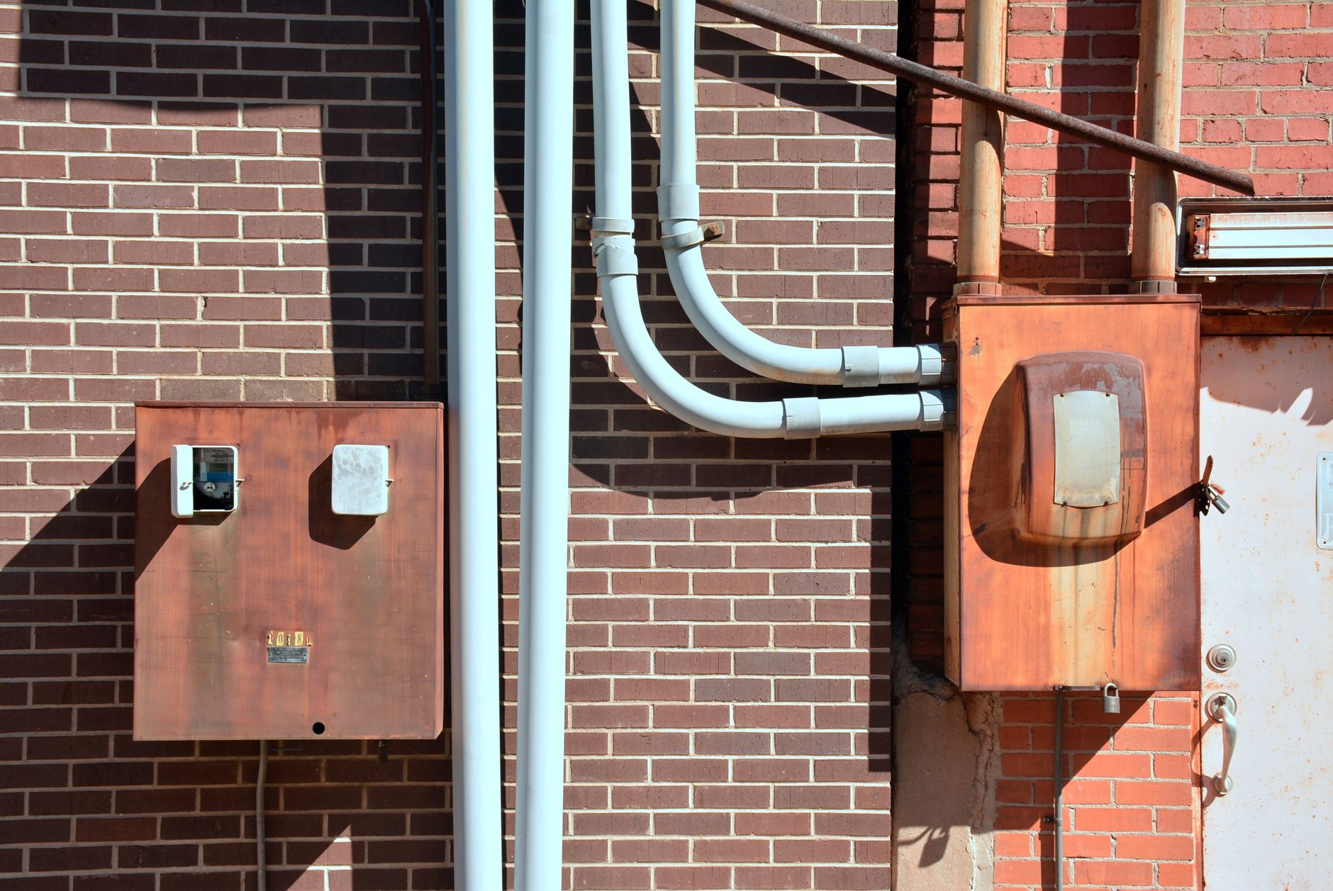 Close-up of industrial utility boxes and piping on a brick wall in Texarkana, Texas.