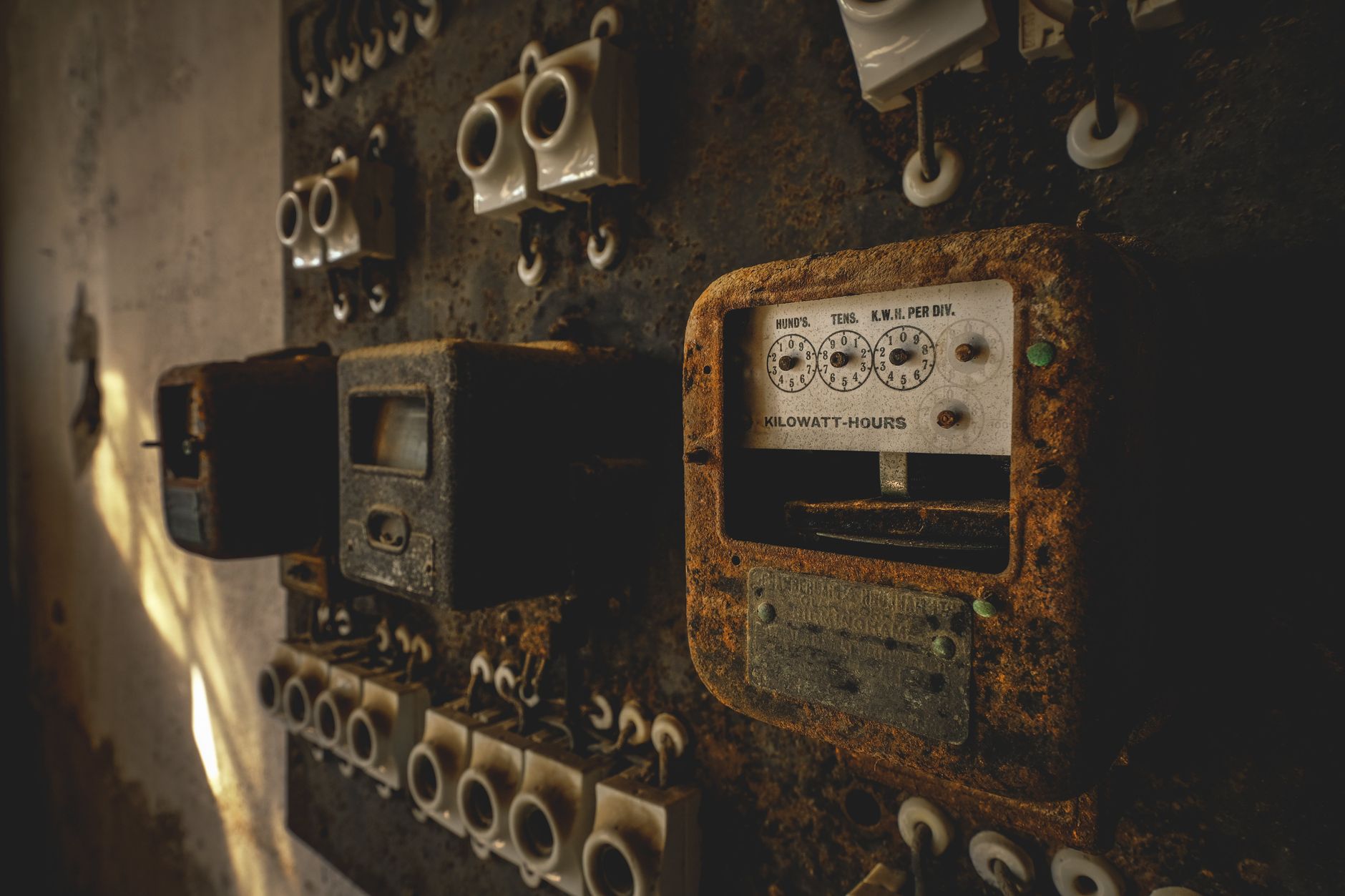 A detailed view of a rusted, vintage electrical control panel indoors.