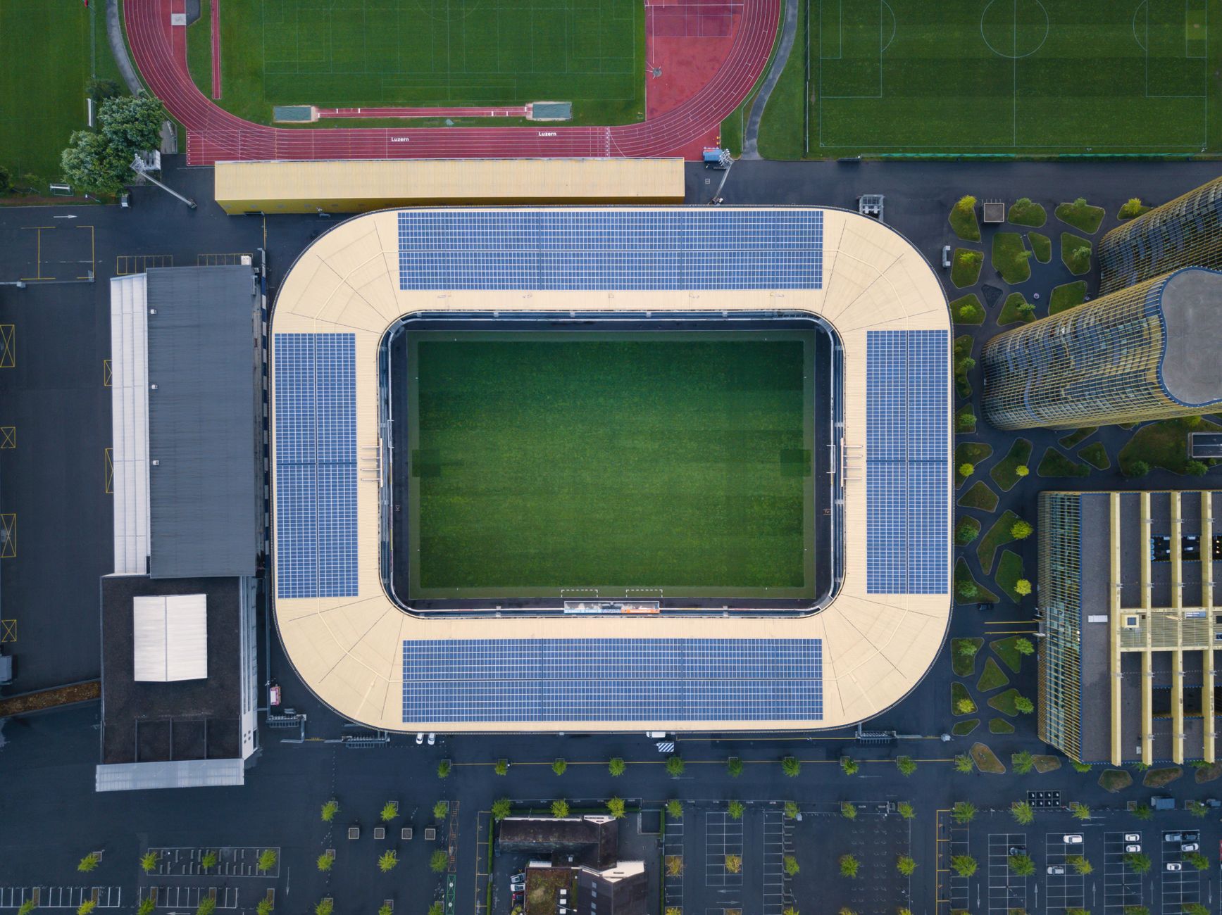 Drone shot of a modern stadium with solar panels and sports fields.