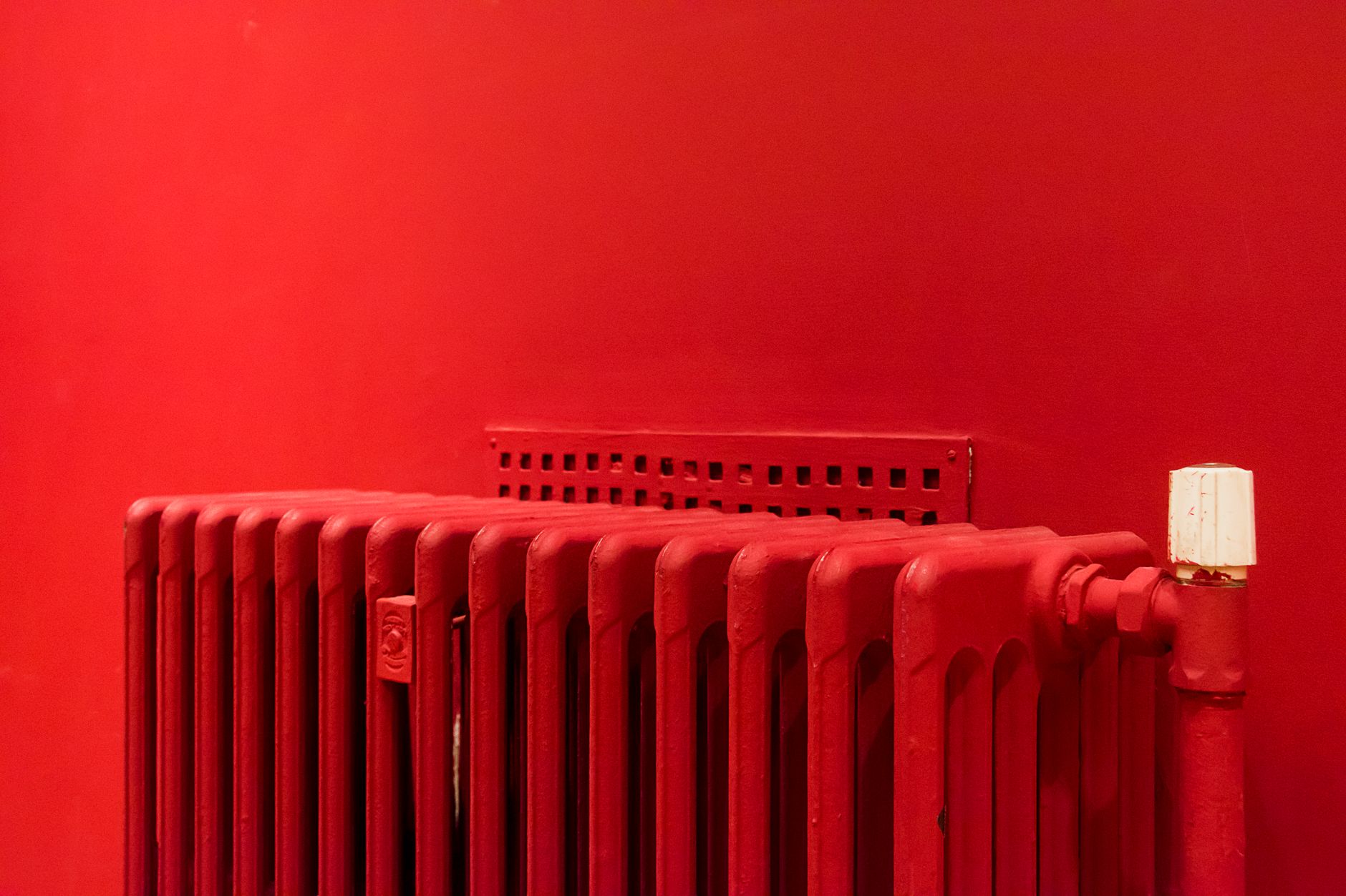 A vibrant red radiator against a matching wall captures minimalist and modern interior design.