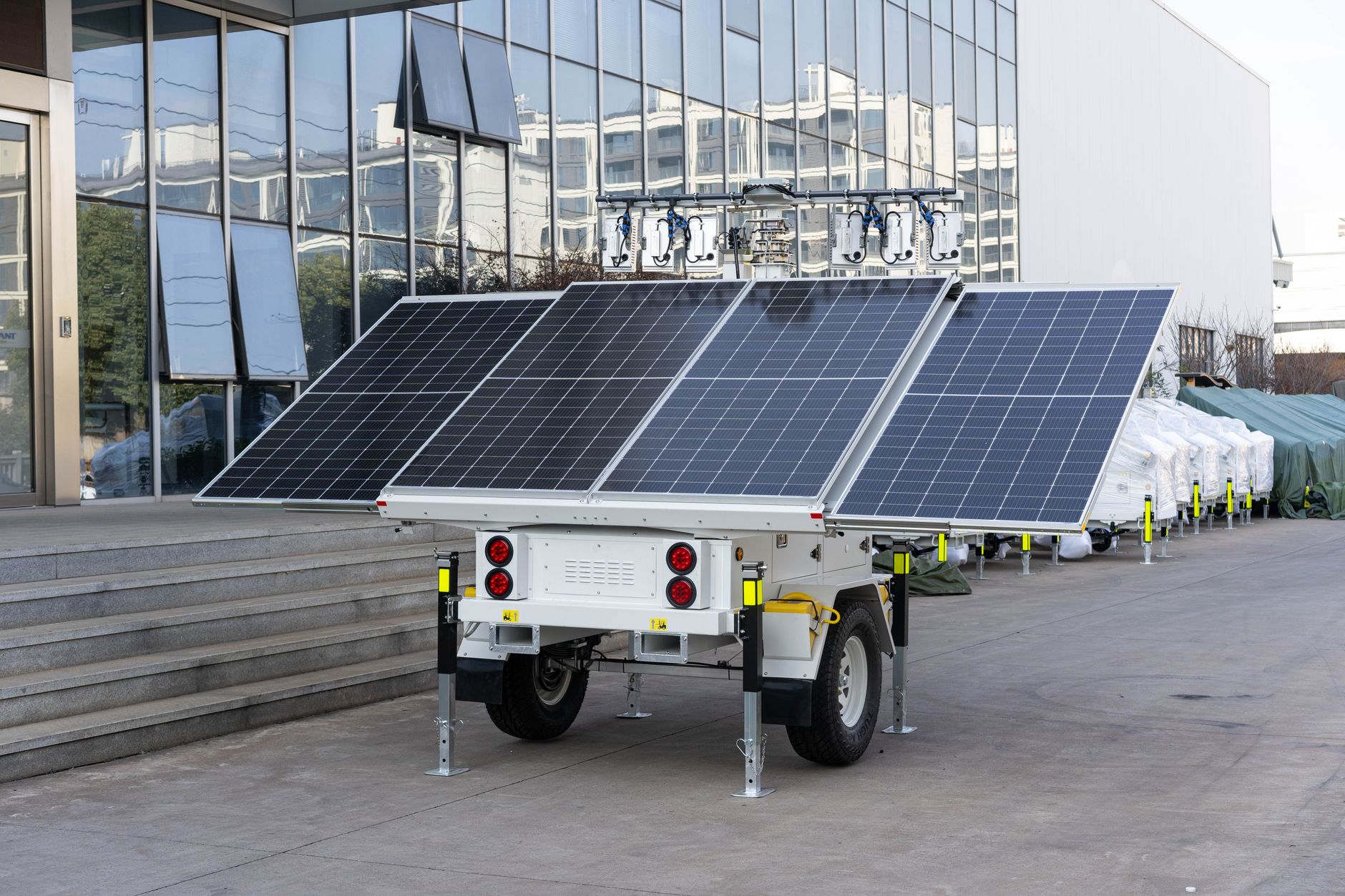 A mobile solar panel trailer parked outdoors by a modern building, showcasing renewable energy technology.
